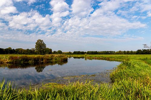 De Dommel op een bewolkte dag. Tussen de wolken door is er een heldere zon.