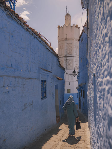Eine marokkanische Frau geht in Richtung einer Moschee in Chefchaouen