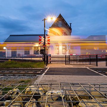Treinstation Cuijk met passerende trein in de avond van Marijke Veltmaat