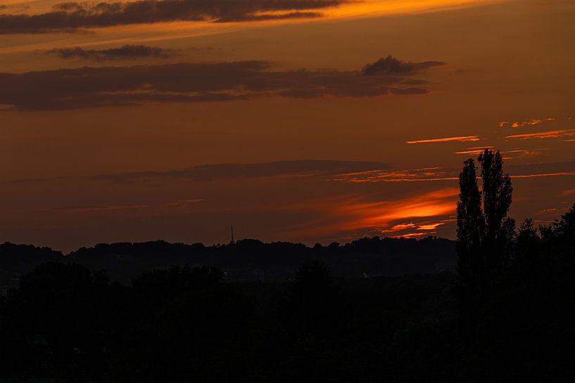 warme zonsondergang met mooie stralen en een heerlijke rood en gele gloed tijdens silhoutte landscha van Kim Willems