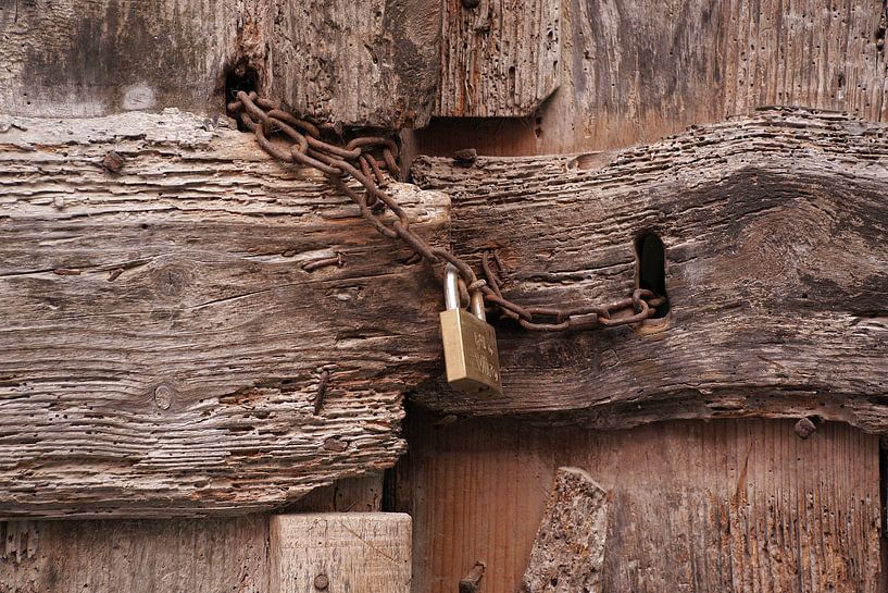 Une porte très délabrée, fermée par une chaîne rouillée et un nouveau cadenas. par Gert van Santen