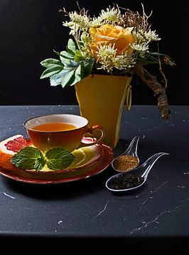 Schwarzer Tee mit Grapefruit in einer Tasse und Löffel mit Rohrzucker