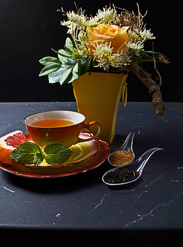 Zwarte thee met grapefruit in een kopje en lepeltje met rietsuiker