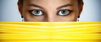 Frauenaugen – Nahaufnahme einer schönen Frau, die sich hinter einem gelben Schleier verbirgt