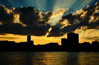 Coucher de soleil à Cologne, rayons de soleil dorés, nuages à la silhouette de ville au ciel bleu.