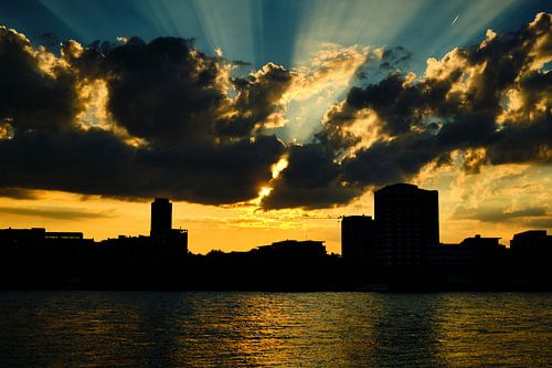 Sunset in Cologne, golden sunbeams, clouds with blue sky city silhouette.