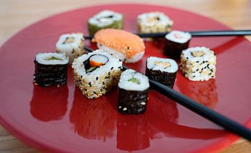Sushi op een rood bord met eetstokjes
