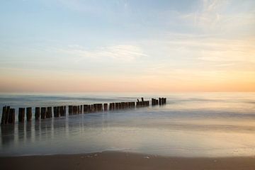 Paaltjes in zee bij zonsondergang