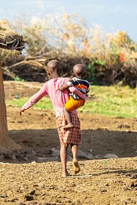Ein Massai-Mädchen mit einem kleinen Kind auf der Hüfte.