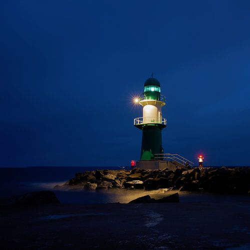 Le phare de la jetée ouest sur la côte de la ville de Warnemünde, la nuit.