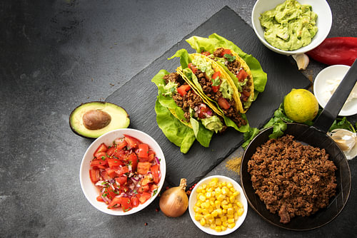 mexikanische Tacos und Zutaten wie gebratenes Hackfleisch, Tomatensalsa, Guacamole, Mais und Gewürze