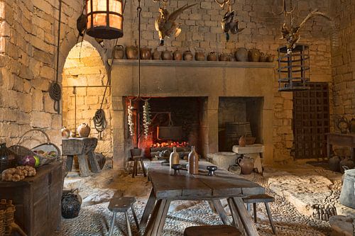 the old kitchen in castle beynac with old pots and pans and wooden furniture