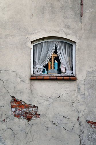 Mur abîmé par les intempéries avec une fenêtre avec des rideaux et une croix avec une statue de Marie