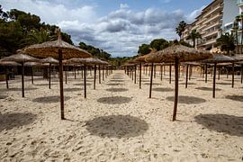 Reihen von Sonnenschirmen an einem leeren Strand auf Mallorca von Wim Brauns