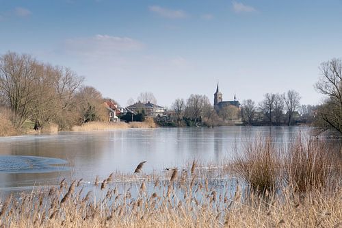 In de Ooijpolder, het water en op de achtergrond een kerkje, Het is winter en koud.