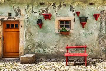 Red bench in front of green house