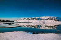 Besneeuwde rots met spiegelreflectie in het water