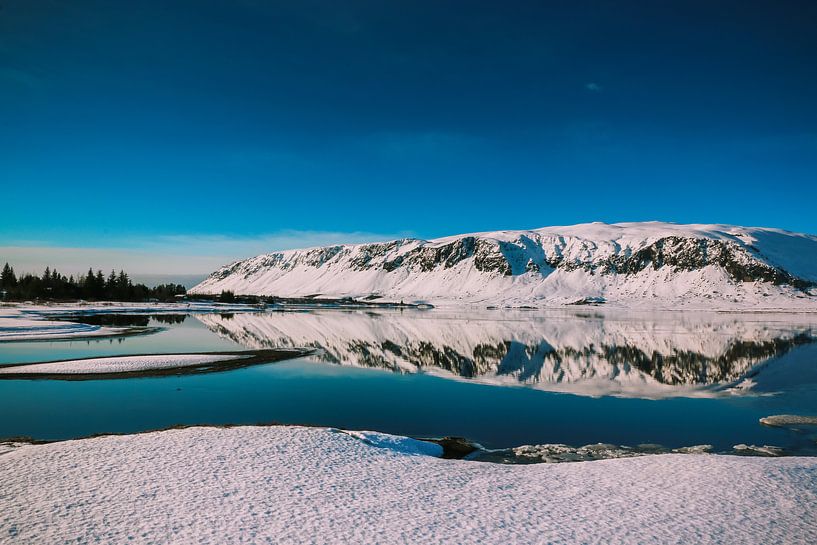 Besneeuwde rots met spiegelreflectie in het water van Jo Pixel