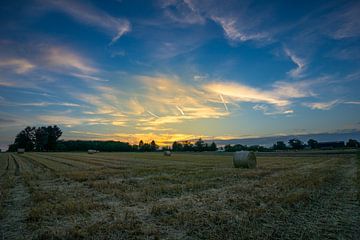 Mooie kleurrijke oranje zonsondergang over veld met hooibalen van adventure-photos