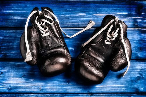 oude bokshandschoenen op blauwe houten achtergrond