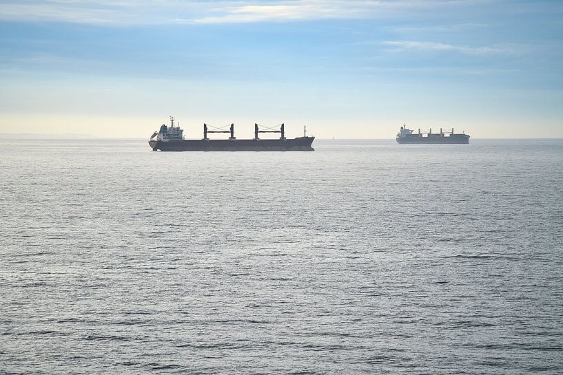 Two cargo ships glide across a calm sea under a clear sky. by Martin Köbsch