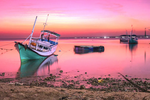 Traditionelles Fischerboot vor dem Hintergrund eines leuchtend rosa Sonnenuntergangs auf der Insel Gili Iyang