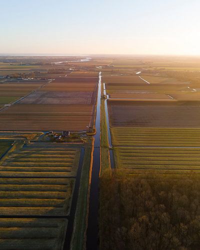 Nederlandse polder vanuit de lucht bij gouden zonsondergang