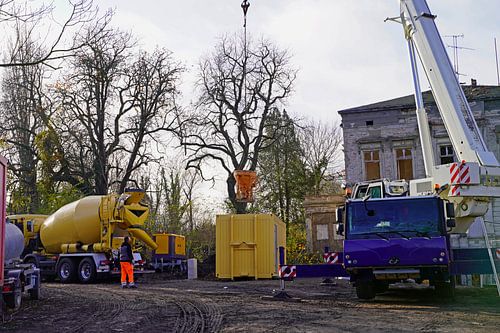 Bouwvoertuigen en -materiaal brengen een betonnen ring aan op een oude graanelevator.