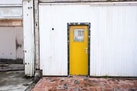 Yellow door in black frame of white building