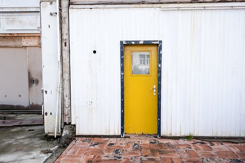 Porte jaune dans le cadre noir d'un bâtiment blanc