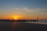 Posts and shadows on the beach at sunset