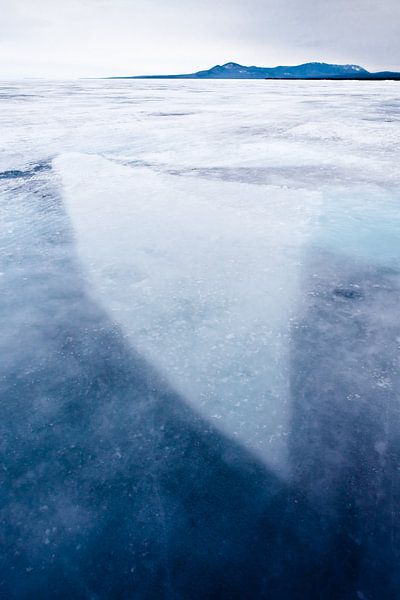ijs bevroren in ijs, een blok bevroren in doorzichtig ijs op het Baikalmeer, bergen in de verte, van Michael Semenov