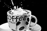 Vallende koffiebonen in een koffie tas met melk