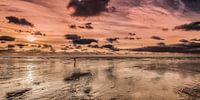 Hardloper op het strand bij eb in het gekleurde avondlicht