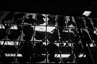 Vue en noir et blanc à travers une vitre d'usine brisée
