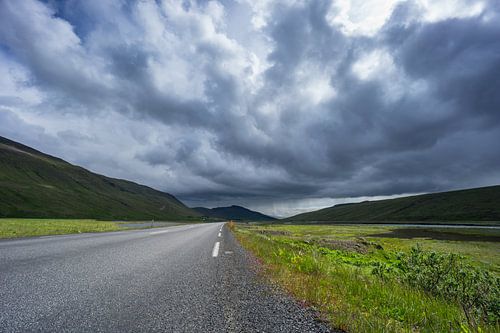 Islande - Route dans une vallée verdoyante et rivière avec pluie au loin
