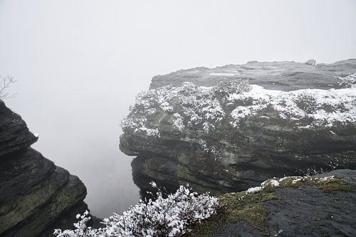 Zschirnstein met besneeuwde rotsen en mist op de top