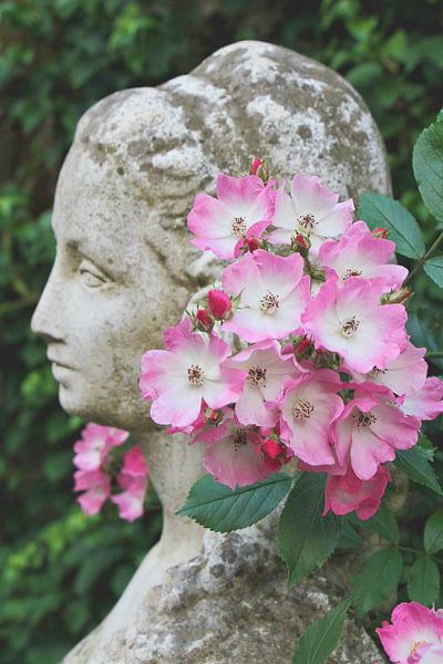 Stone sculpture woman with climbing roses by Anne Wil Stegeman