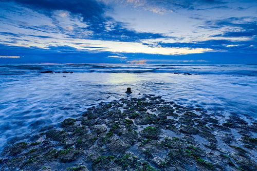 zonsondergang langs de Noordzee met een typische golfbreker in de voorgrond