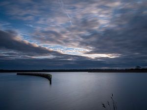 Rij Palen in Stil Water bij Zonsondergang