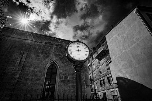 Zwartwit foto van een staande klok in een Italiaans dorp.