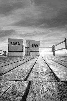 Beach chairs by the sea at sunset in black and white .