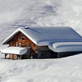 Deep snow covered alpine hut on a sunny winter day by chamois huntress