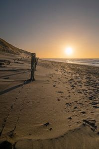 Strand mit Fußspuren und tief stehender Sonne