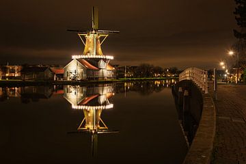 Verlichte molen met weerspiegeling in het water in Nederland