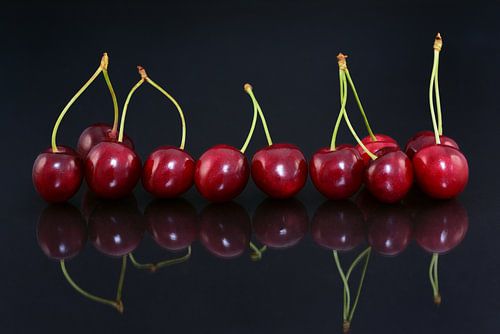 Red cherries are reflected on the table