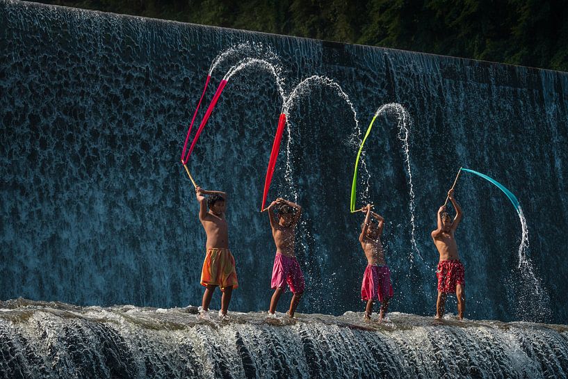 Balinese jongens spelen met gekleurde lappen stof op de Tukad Unda waterdam in Bali van Anges van der Logt