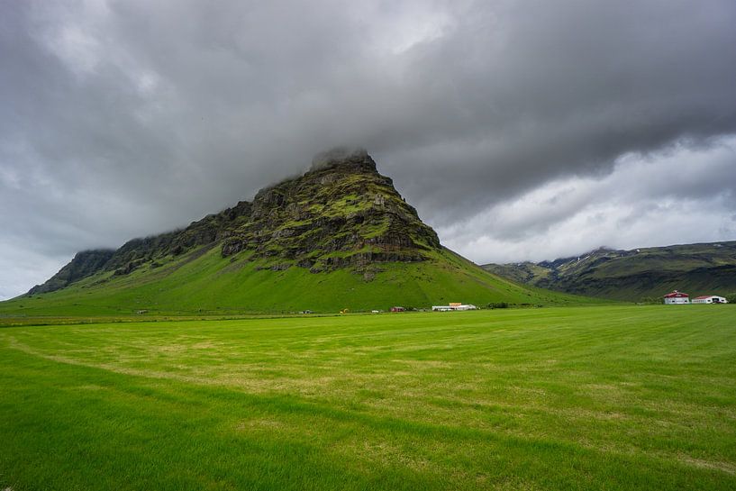 Island - Moosbewachsener Berg hinter grünem Feld mit Häusern von adventure-photos