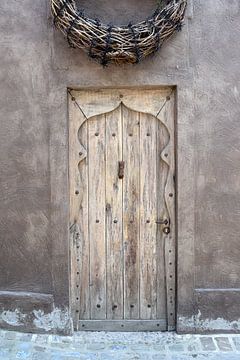 Oude houten deur met rieten krans erboven van Nicolette Vermeulen