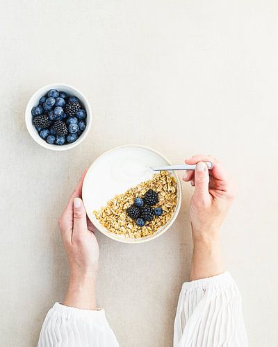 Deux mains, un bol de granola aux myrtilles